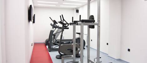 A gym with cardio machines, weightlifting equipment, and a red carpet path.