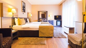 Una habitación de hotel con una cama grande, lámparas de noche, un televisor y un escritorio.