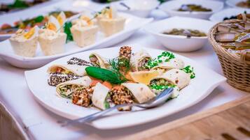 A buffet table with various dishes, including wraps and small appetizers.