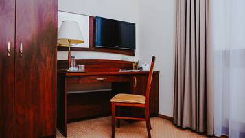 Une chambre d’hôtel avec un bureau en bois, une télévision, une lampe et une chaise.