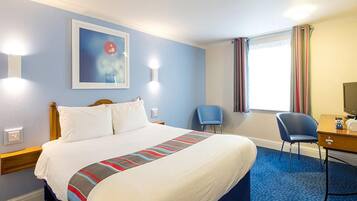 Una habitación de hotel con una cama grande, un escritorio, una silla y una ventana con cortinas.