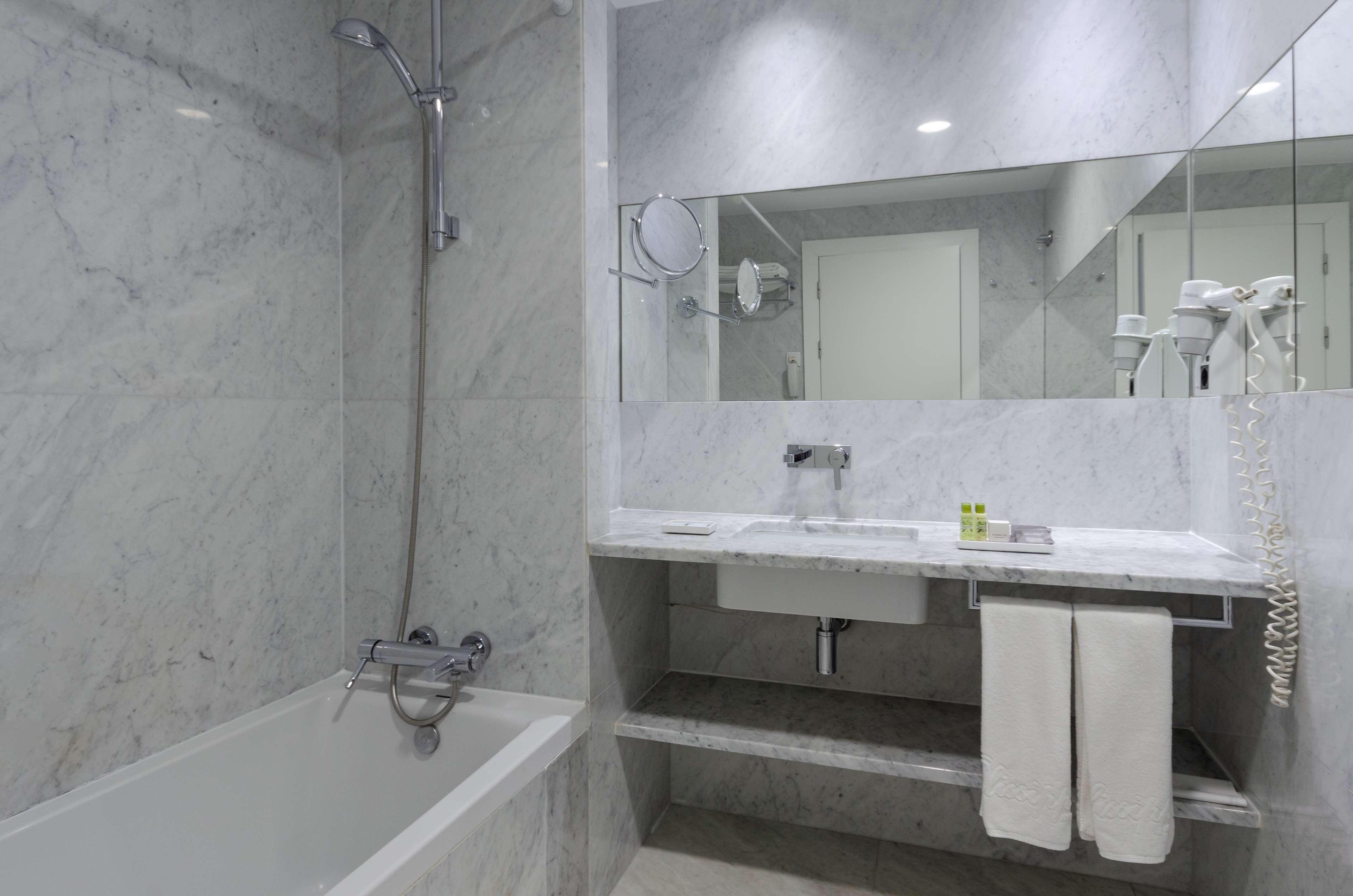 A modern bathroom with a bathtub, a sink, and a mirror.