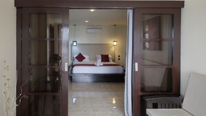 Habitación de hotel con cama, sofá y puerta corredera que da a otra habitación.