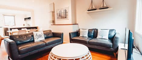 Un salon moderne avec deux canapés en cuir, une table basse ronde et un téléviseur à écran plat.