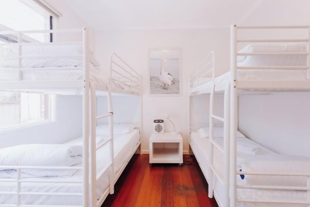 A room with bunk beds, a small table, and a window.
