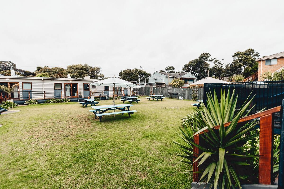 A grassy backyard with picnic tables and a wooden fence.