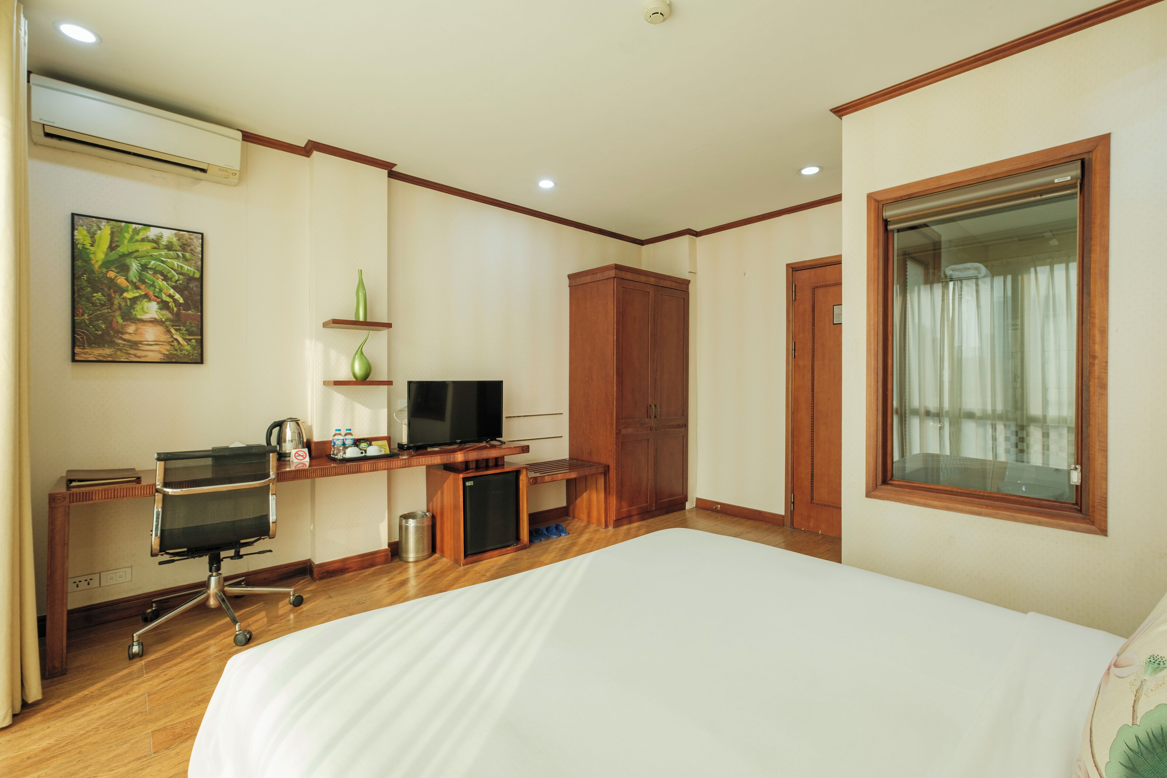 A hotel room with a bed, desk, TV, wardrobe, and a window.