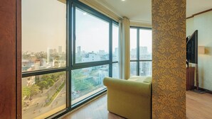 Una habitación con ventanas amplias, un sofá, un televisor y un papel tapiz estampado.