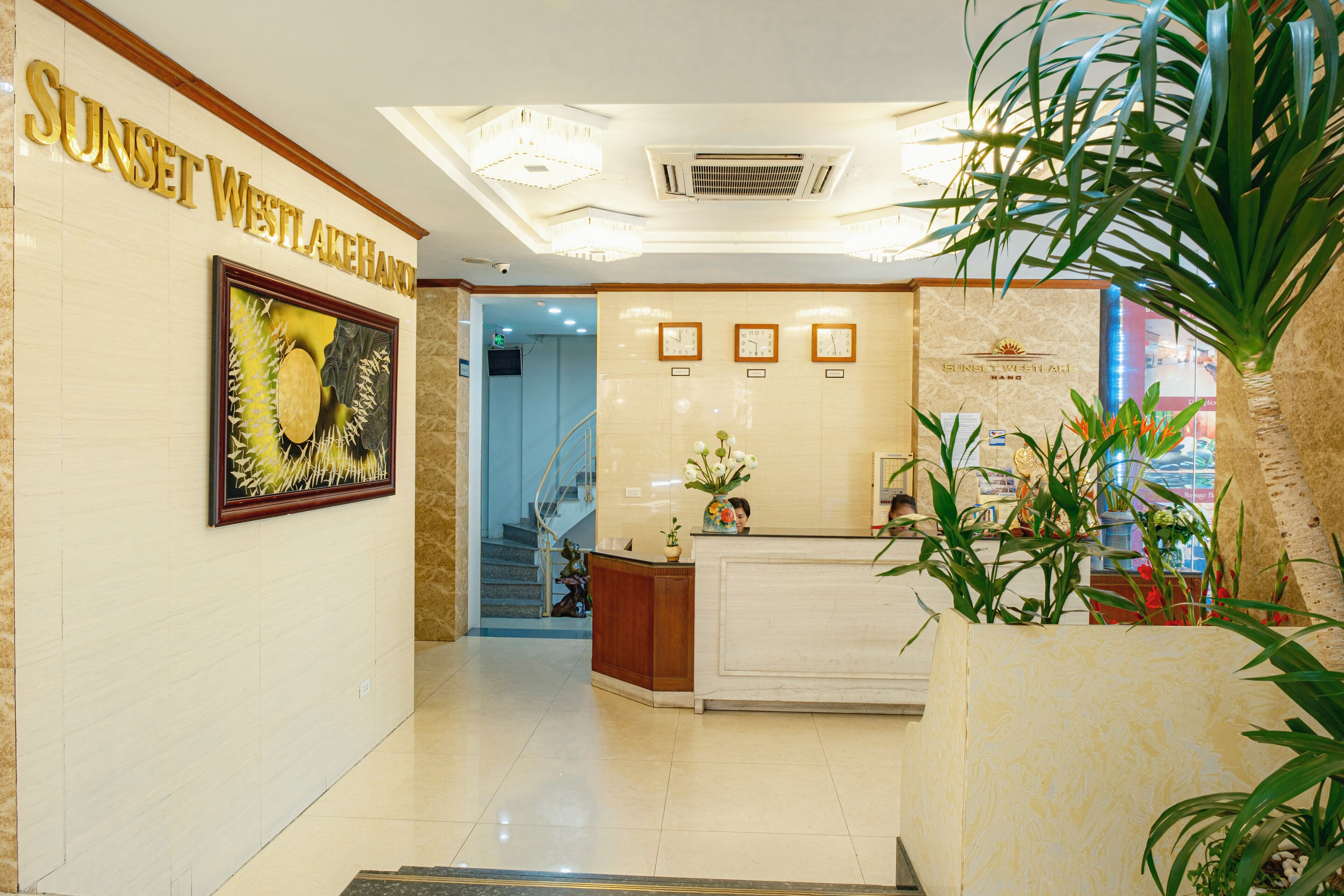 A reception area with a reception desk, framed artwork, and a staircase leading to an upper floor.