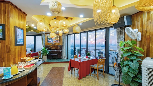 Un comedor con bufé, ventanas amplias y lámparas de mimbre colgantes.