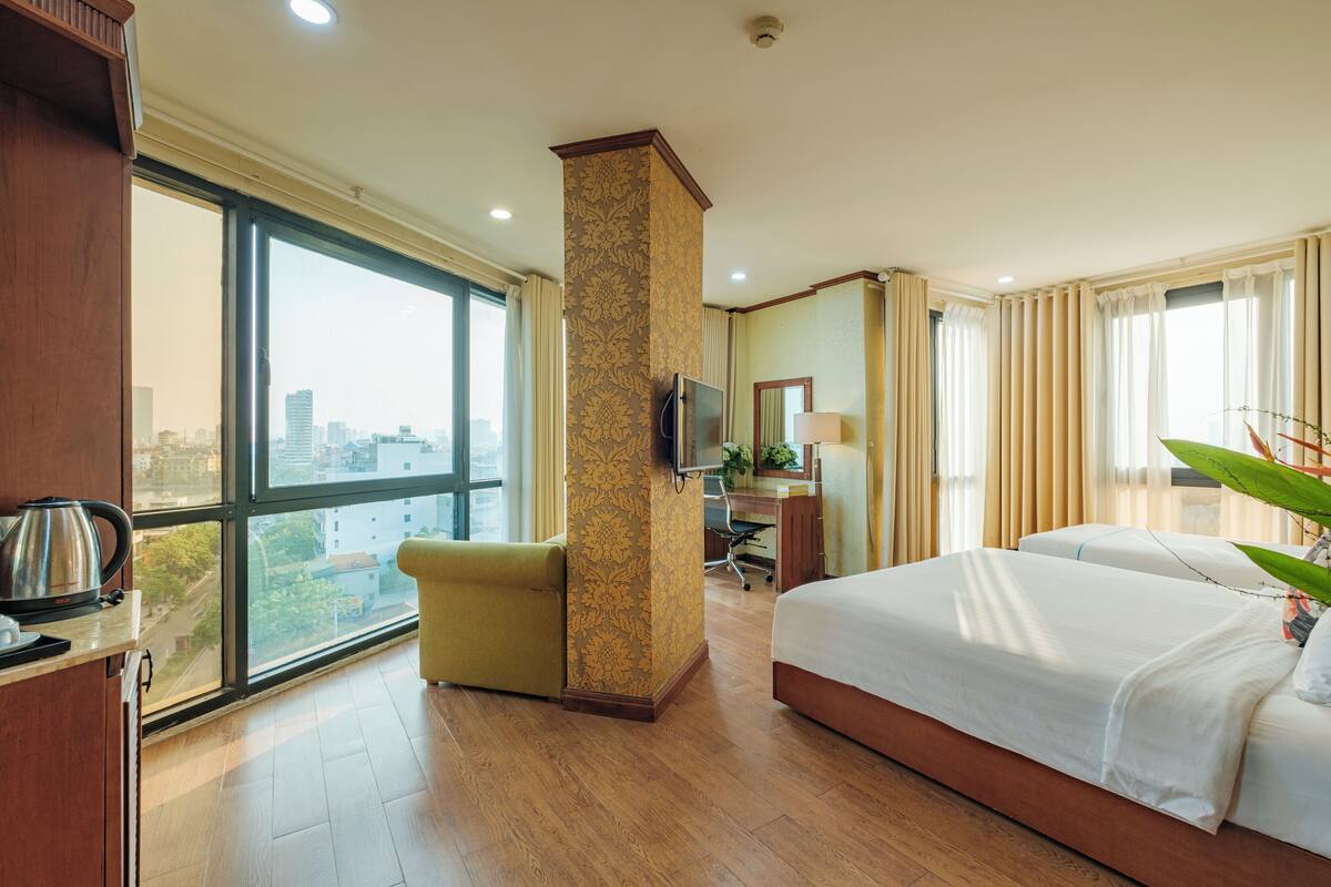 Una habitación de hotel con un ventanal grande, una cama, un escritorio y una silla.