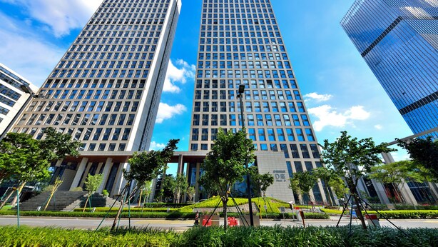 A modern high-rise building with a grid of windows, surrounded by greenery and other buildings. - Guangzhou Heefun Apartment - Poly World Trading (Guangzhou)