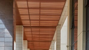 A covered walkway with a tiled floor, large pillars, and a wooden ceiling. - Guangzhou Heefun Apartment - Poly World Trading (Guangzhou)