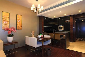Una habitación de hotel moderna con comedor, cocina y obras de arte en las paredes.