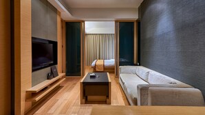 A modern hotel room with a flat-screen TV, a sofa, a small coffee table, and a bed with curtains. - Guangzhou Heefun Apartment - Poly World Trading (Guangzhou)