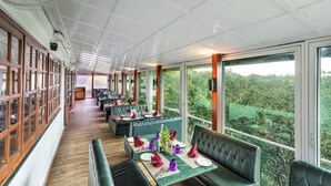 Un restaurant doté de planchers en bois, de banquettes vertes et de tables dressées avec des serviettes et des assiettes violettes.