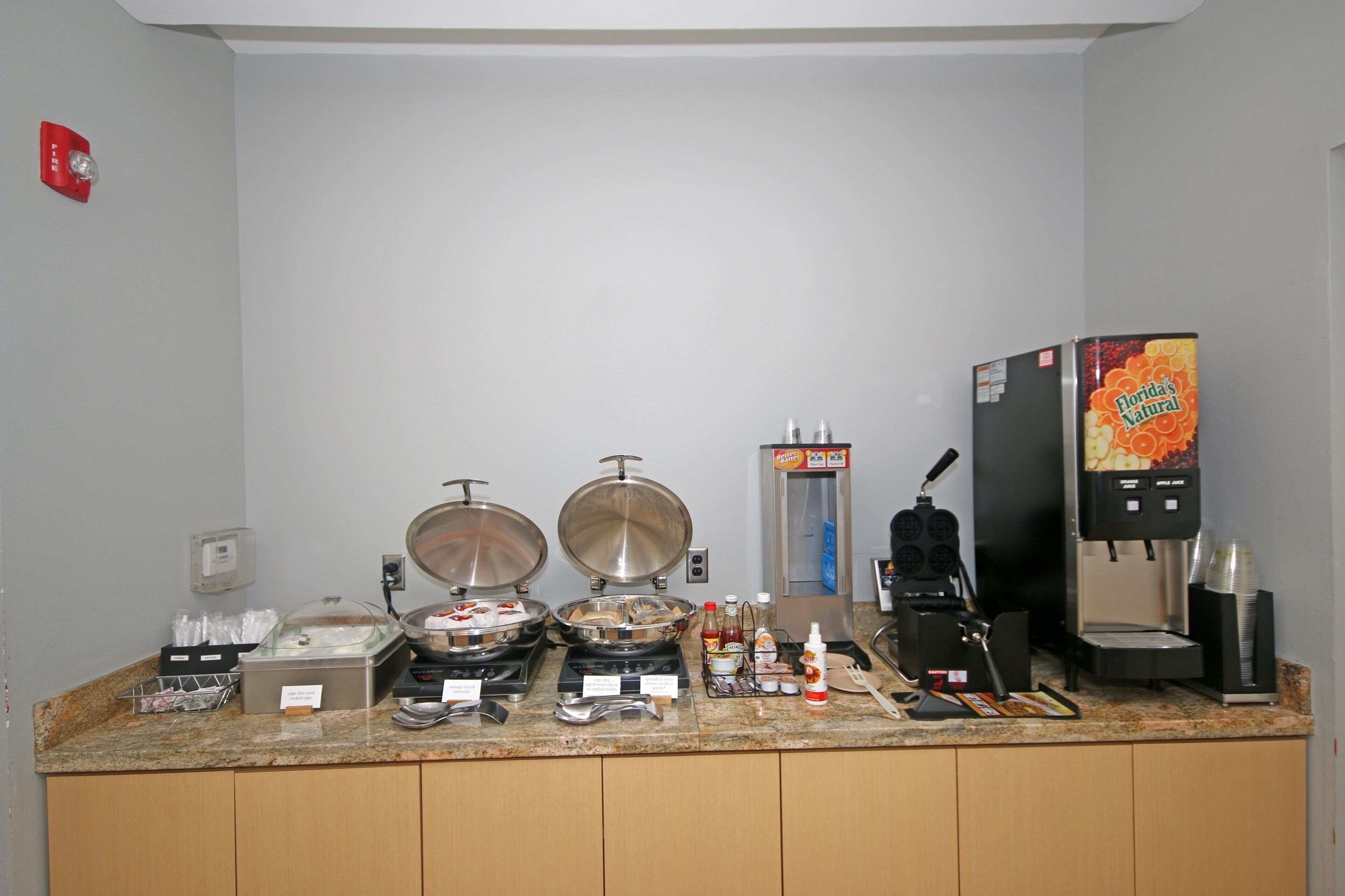 A buffet setup with a coffee machine, a refrigerator, and various food containers.