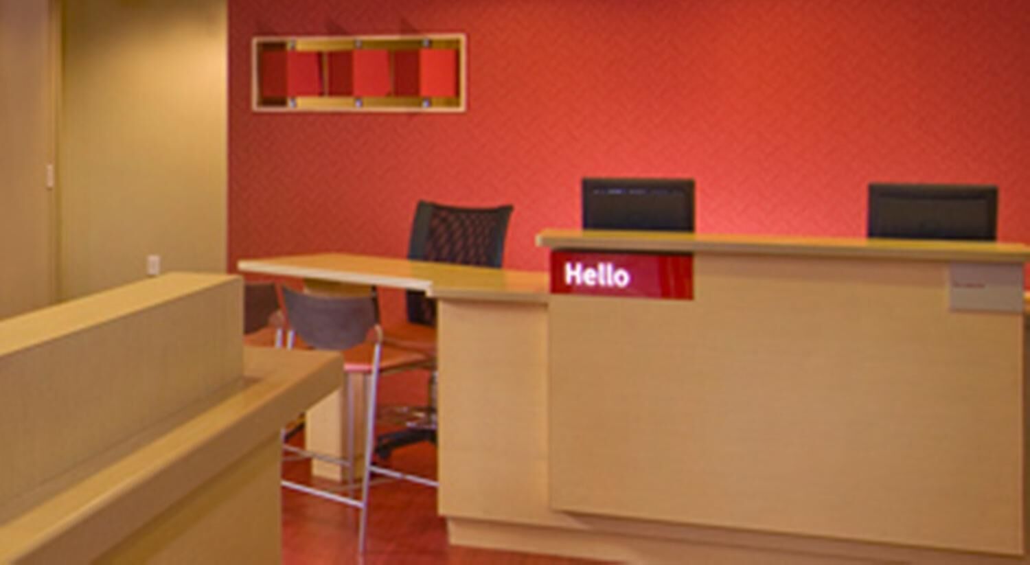 A reception desk with a 'Hello' sign, a chair, and a small table.
