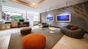 Un hall d’hôtel moderne, doté d’un comptoir d’accueil, d’espaces aménagés pour s’asseoir et d’œuvres d’art accrochées aux murs.