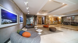 Un hall d’entrée moderne, doté d’espaces aménagés avec des sièges, d’un comptoir de réception et d’œuvres d’art accrochées aux murs.