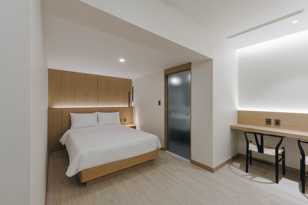Una habitación de hotel moderna con una cama, un escritorio y una silla.