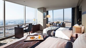A hotel room with a large bed, a desk with a chair, a dining table with breakfast, and a view of the city. - Sono Calm Goyang (Goyang)
