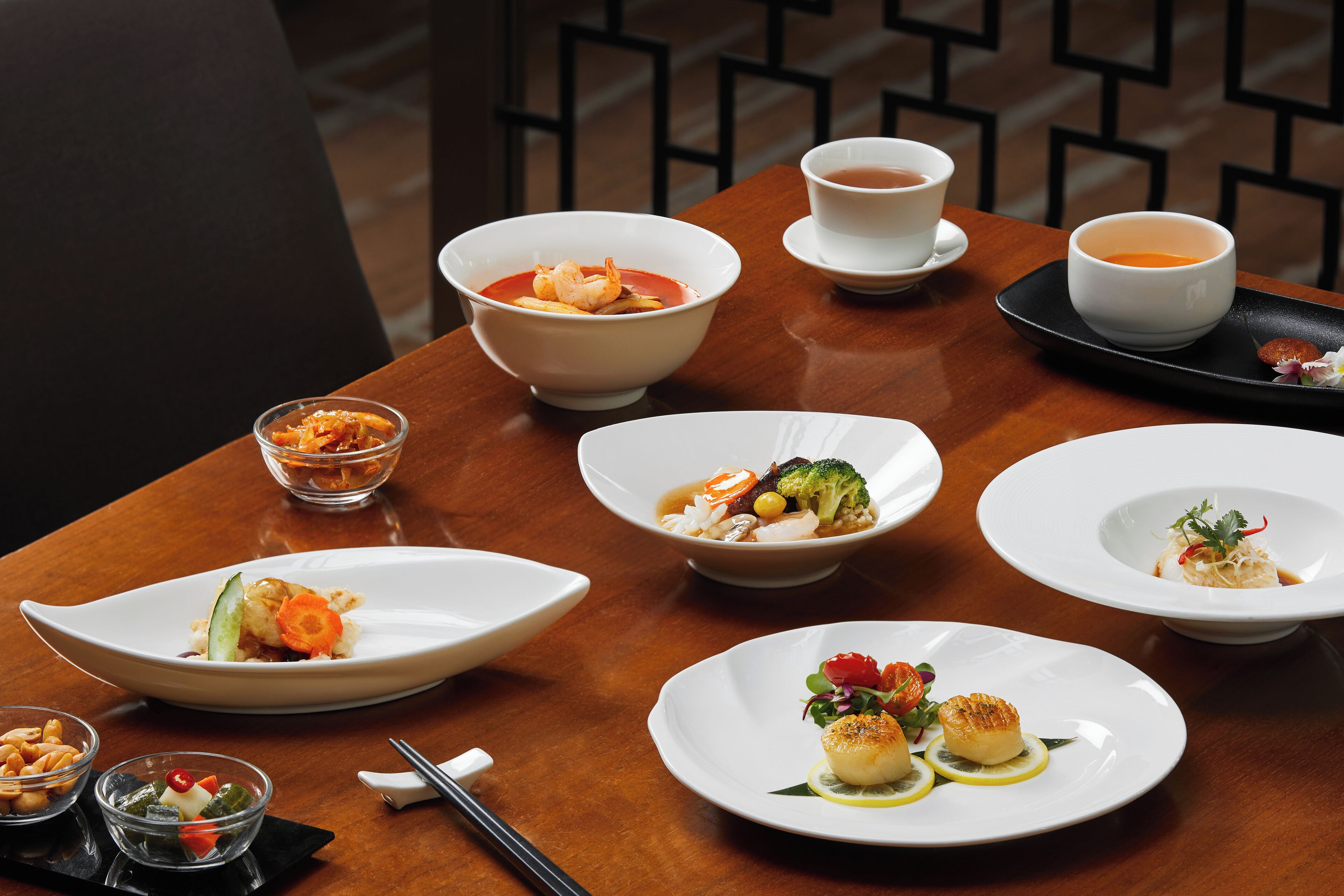 A dining table with various dishes and bowls of food, including seafood and vegetables, arranged on white plates.