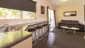 A compact living space with a kitchenette, a sofa, and a coffee table. - Red Rock Thermal Motel (Rotorua)