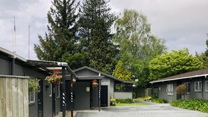 A building with a paved driveway leading to a gated entrance. - Red Rock Thermal Motel (Rotorua)