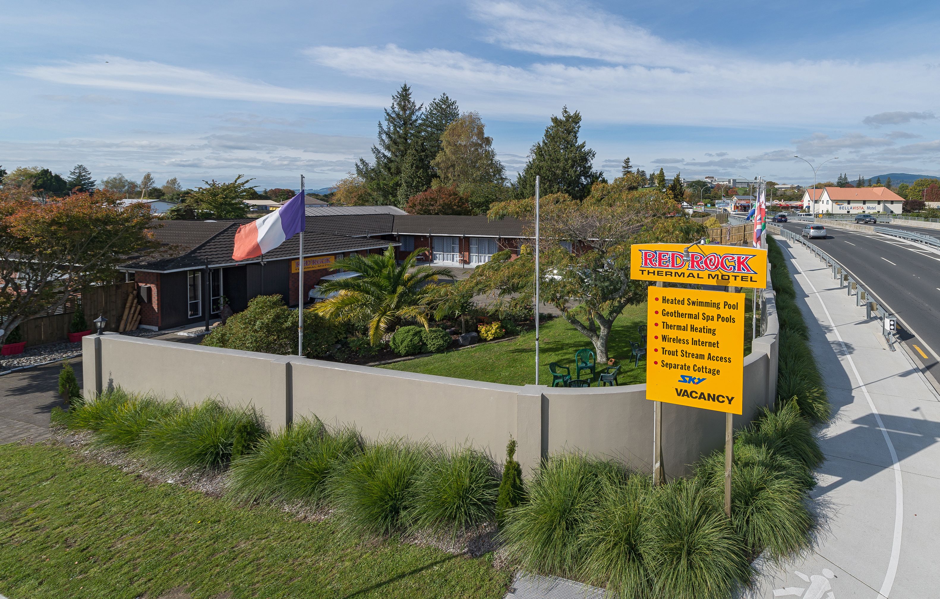 A motel sign with amenities including a heated swimming pool, geothermal spa, thermal heating, wireless internet, trout stream access, and a separate cottage.