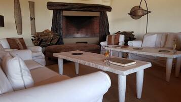 Una sala de estar acogedora con sofás blancos, una mesa de centro de madera y una chimenea.