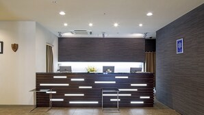 Ein Empfangsbereich im modernen Design, mit einem dunklen Holzbüro, zwei Metallstühlen und einem an der Wand befestigten Schild.