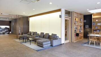 Eine moderne Lobby mit einer Eckcouch, einem Couchtisch, einem Bücherregal und einer Rezeption.