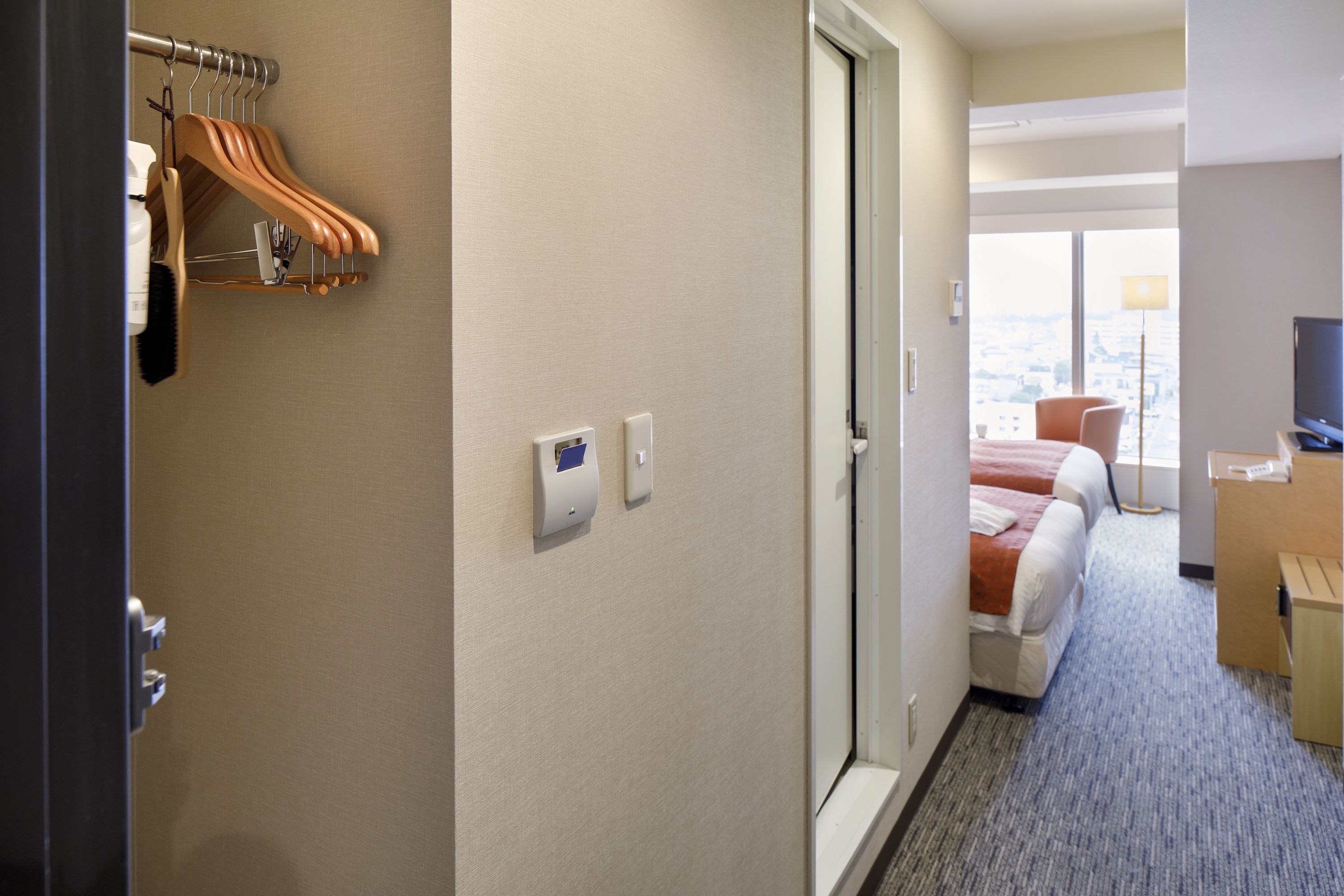 A hotel room with a bed, a desk, a TV, and a window with a view.