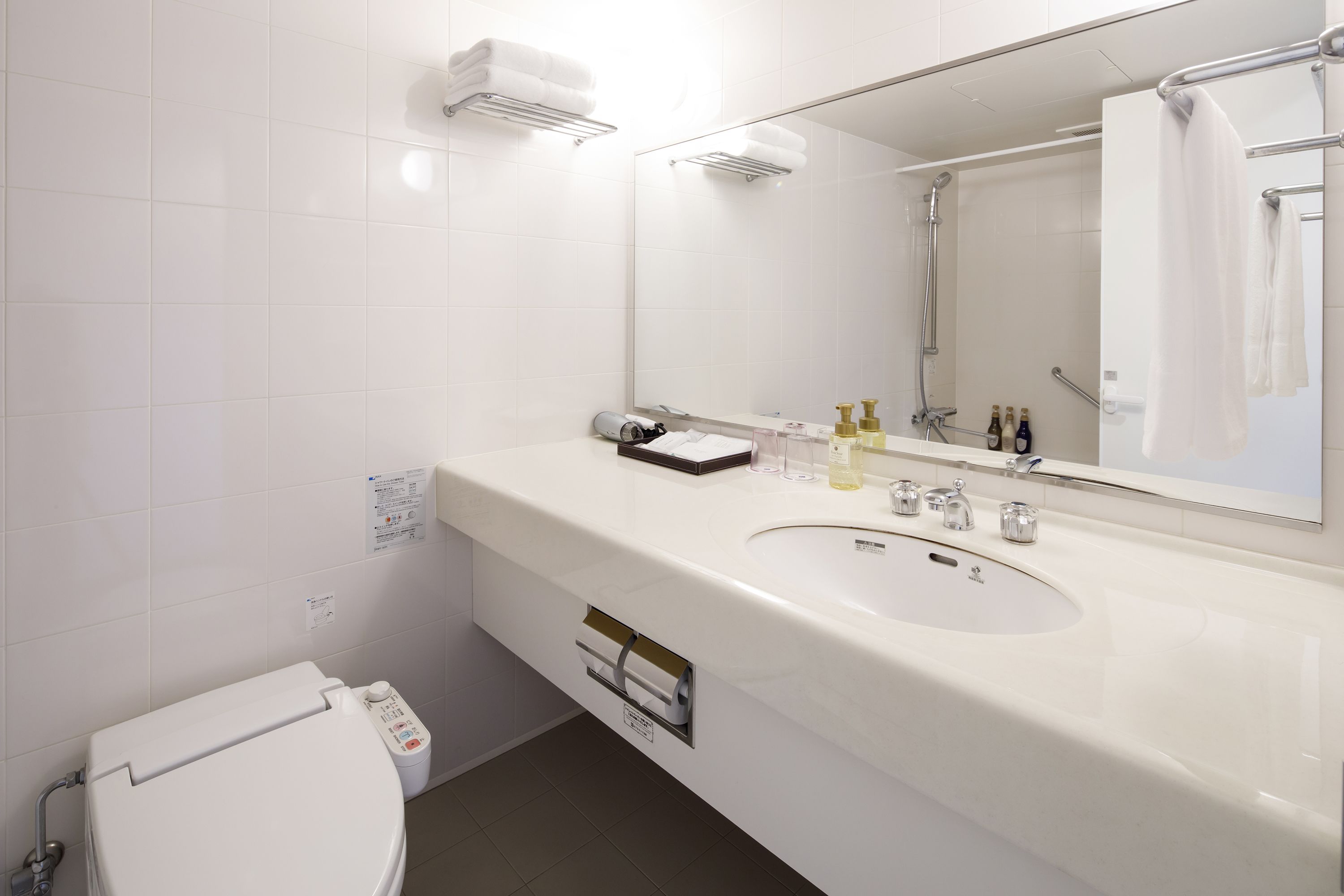 A modern bathroom with a white sink, mirror, and toilet.