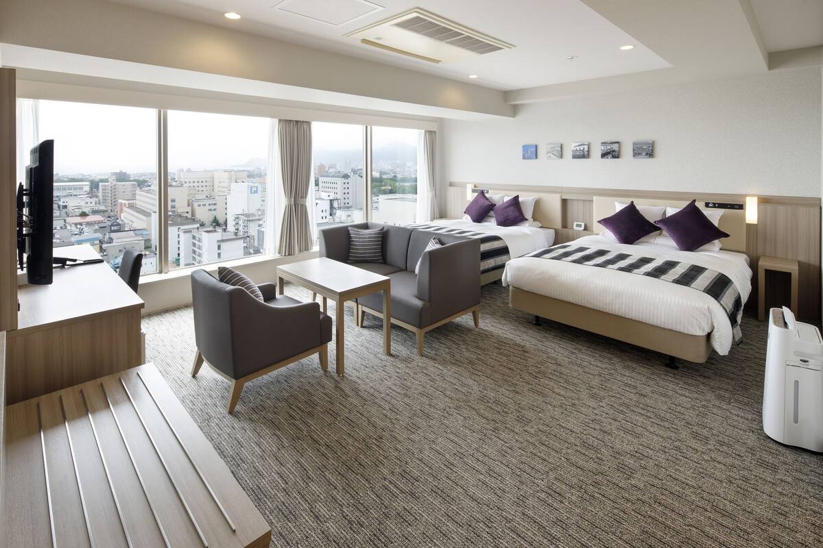 Una habitación de hotel moderna con una cama grande, un sofá, un escritorio y vistas a la ciudad.
