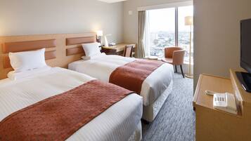 A hotel room with two beds, a desk, a chair, a TV, and a phone.