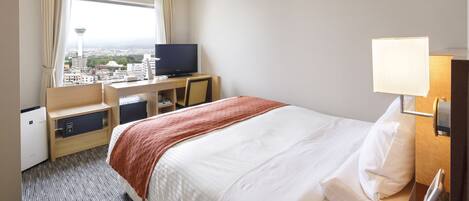 Habitación de hotel con cama, escritorio, computadora, televisión y vista panorámica de la ciudad.
