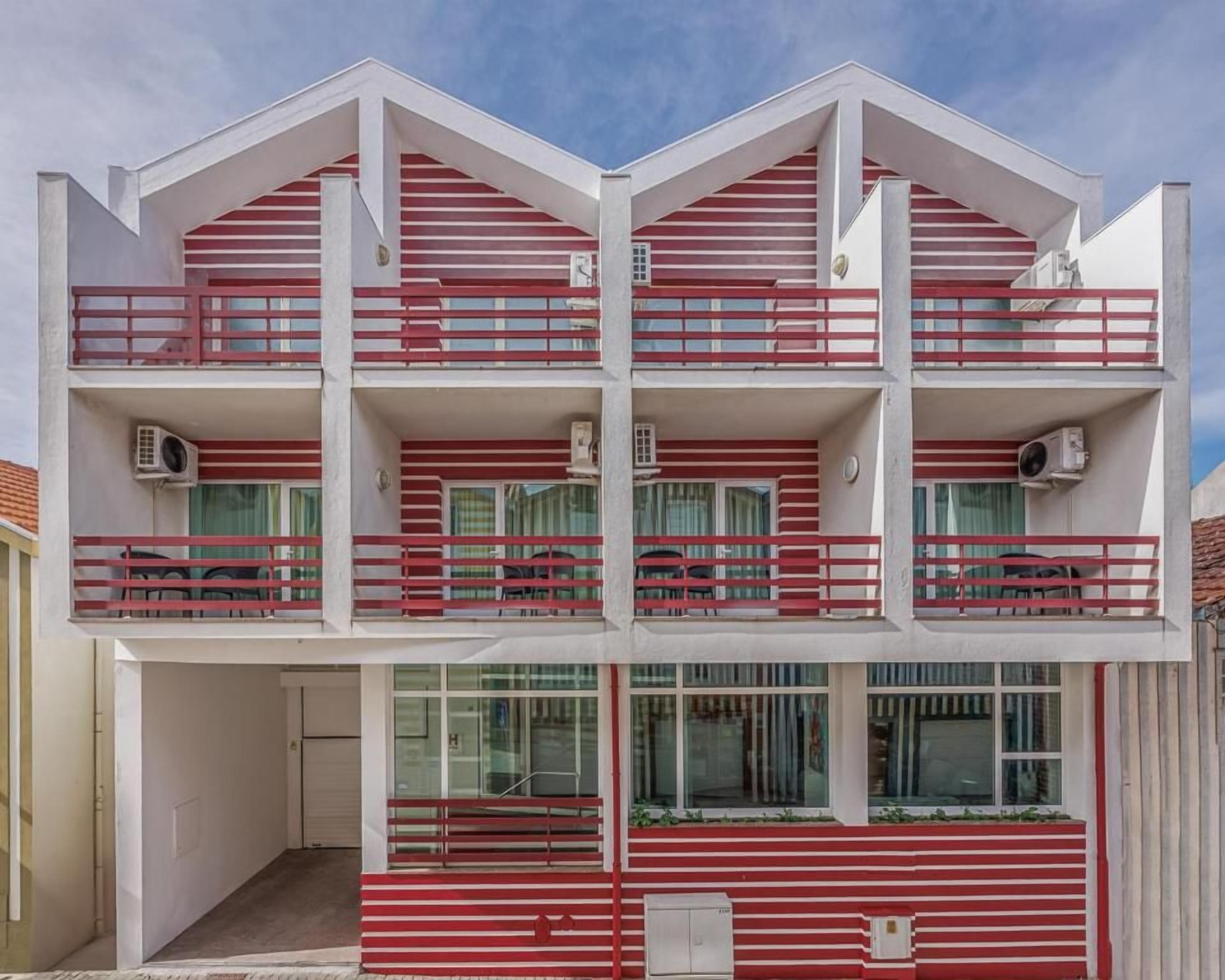 Un edificio de varios pisos con balcones, unidades de aire acondicionado y un cielo despejado.