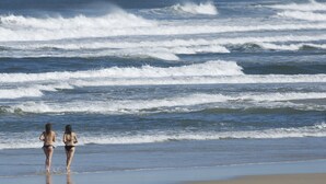 A beach scene with two people walking along the shore. - Costa Nova Hotel (Ilhavo)