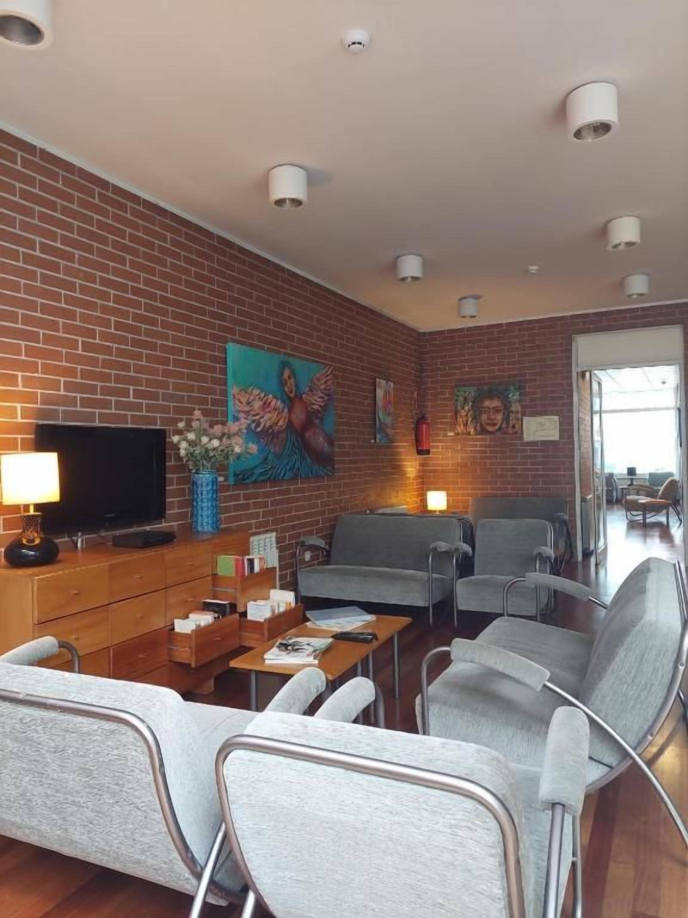 A modern living room with a brick wall, a flat-screen TV, a sofa, a coffee table, and a fireplace.