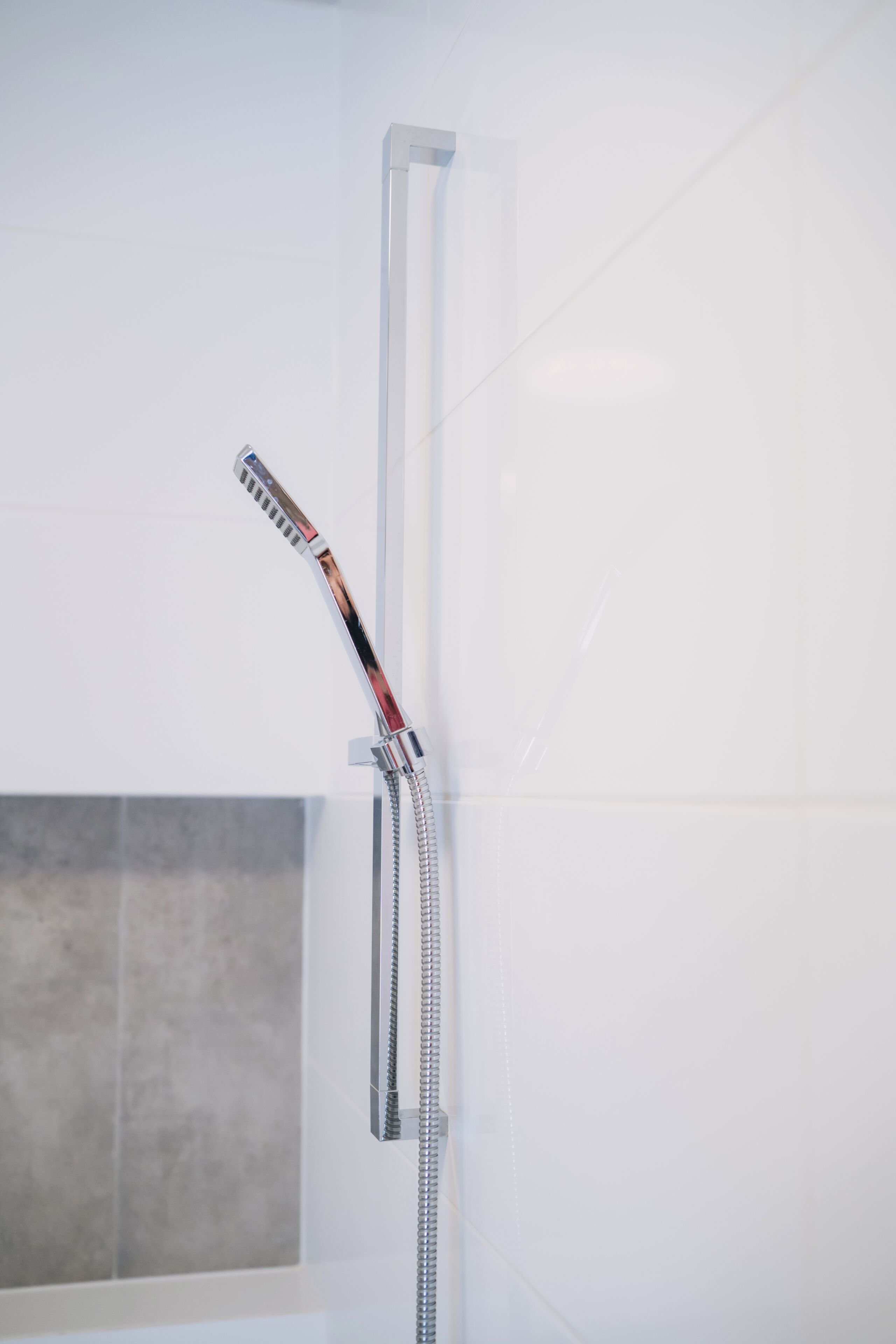 Una ducha con grifo de cromo y manguera flexible.