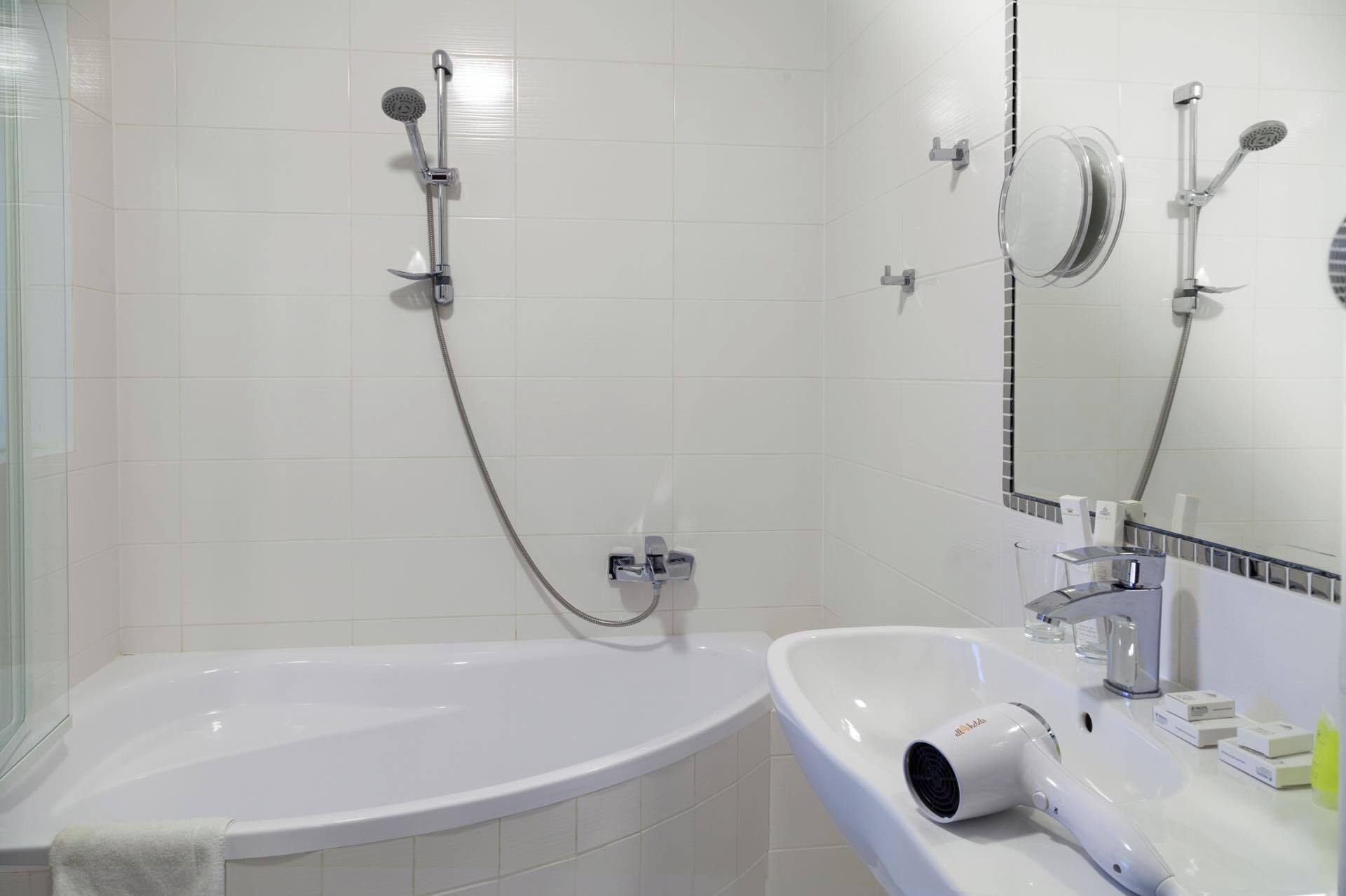 A modern bathroom with a bathtub, a shower, and a sink with a hairdryer.