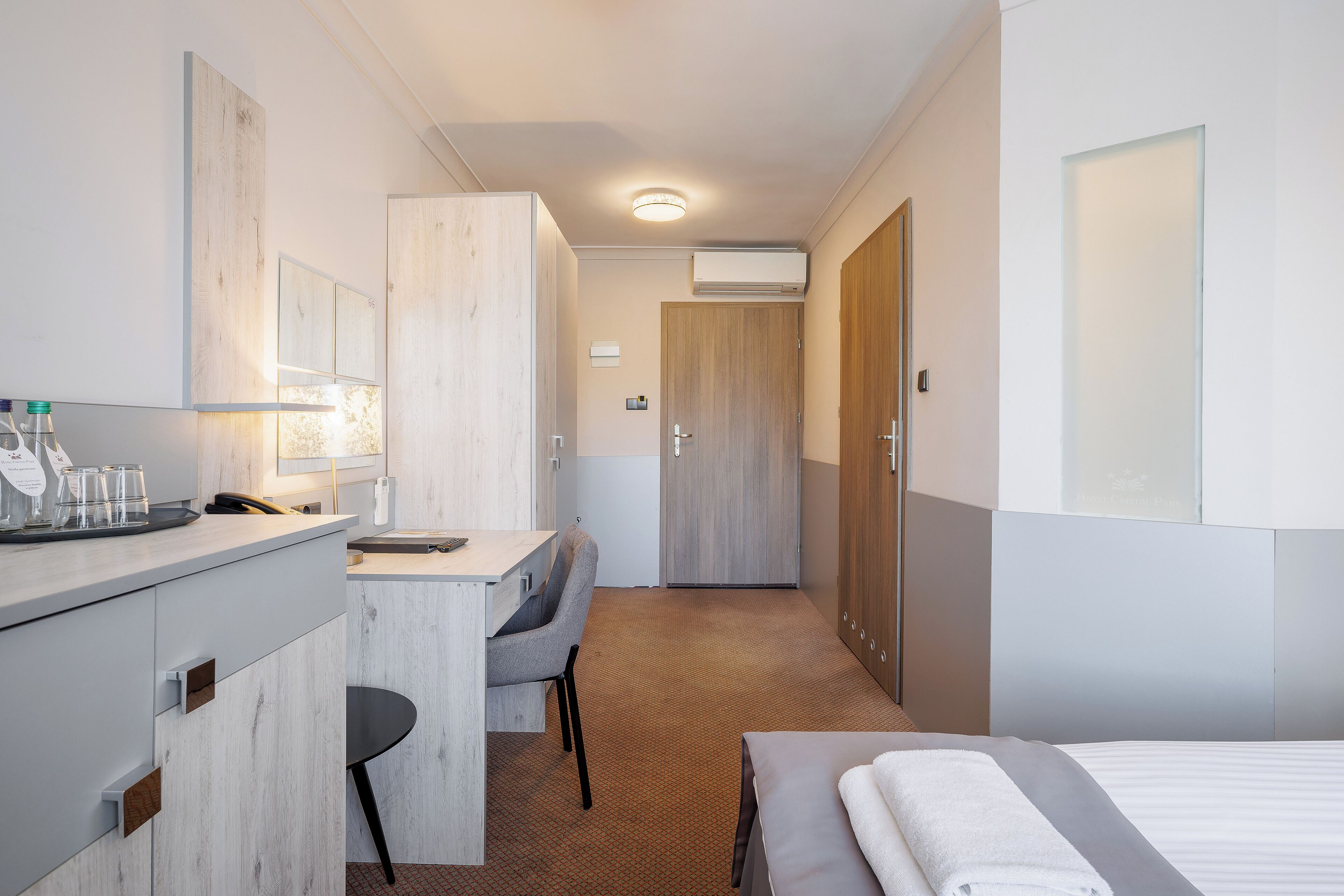 Une chambre d’hôtel comprenant un lit, un bureau, une chaise, une armoire et une salle de bain.