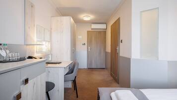 Une chambre d’hôtel comprenant un lit, un bureau, une chaise, une armoire et une salle de bain.