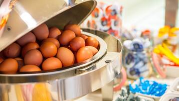 A buffet with a large pot of eggs and various food items in the background.