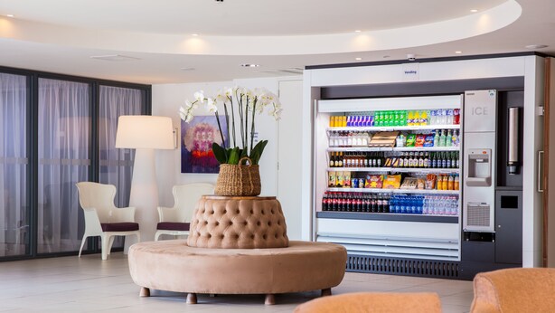 A modern hotel lobby with a plush seating area, a vending machine, and a refrigerator stocked with beverages. - Holiday Inn Express Arnhem by IHG (Arnhem)