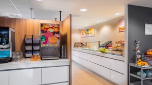 A modern breakfast area with a coffee machine, beverage dispensers, and a fruit display. - Holiday Inn Express Arnhem by IHG (Arnhem)