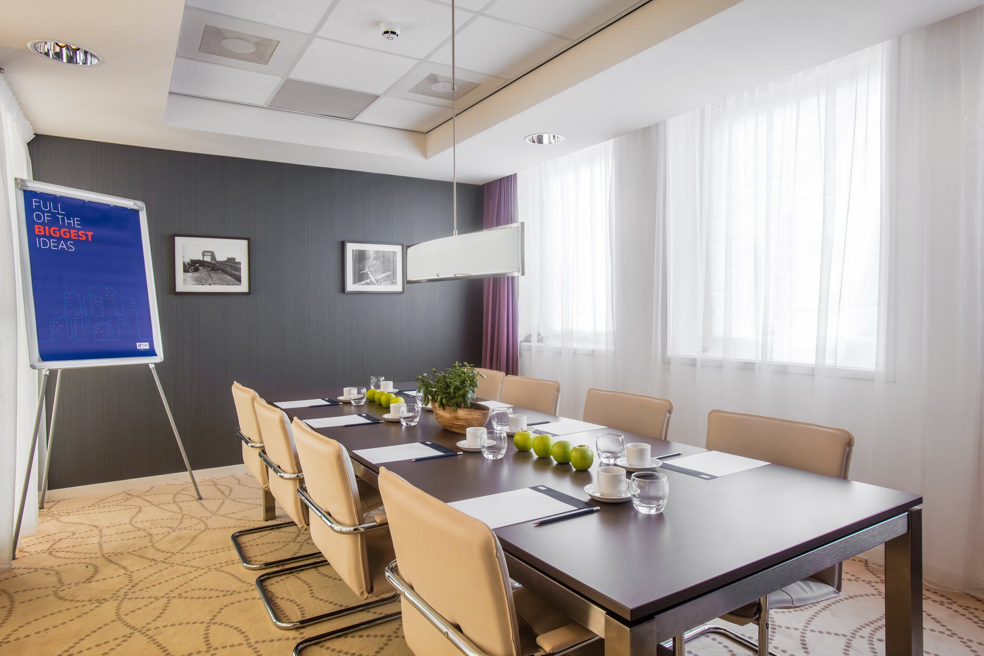 A conference room with a large table, chairs, a whiteboard, and framed pictures on the wall.