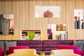 A modern living room with a wooden wall, a purple sofa, a green vase, and a red woven basket. - Holiday Inn Express Arnhem by IHG (Arnhem)